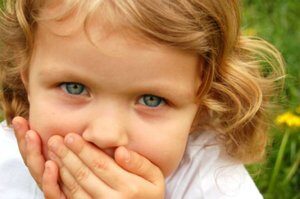 Little girl with her hands over her mouth