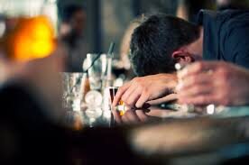 Person with his head on the table and empty bottles surrounding him