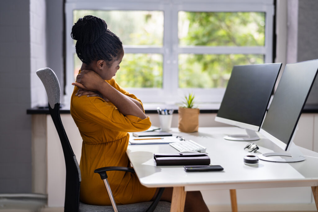 Female working at desk holding her neck because of neck pain