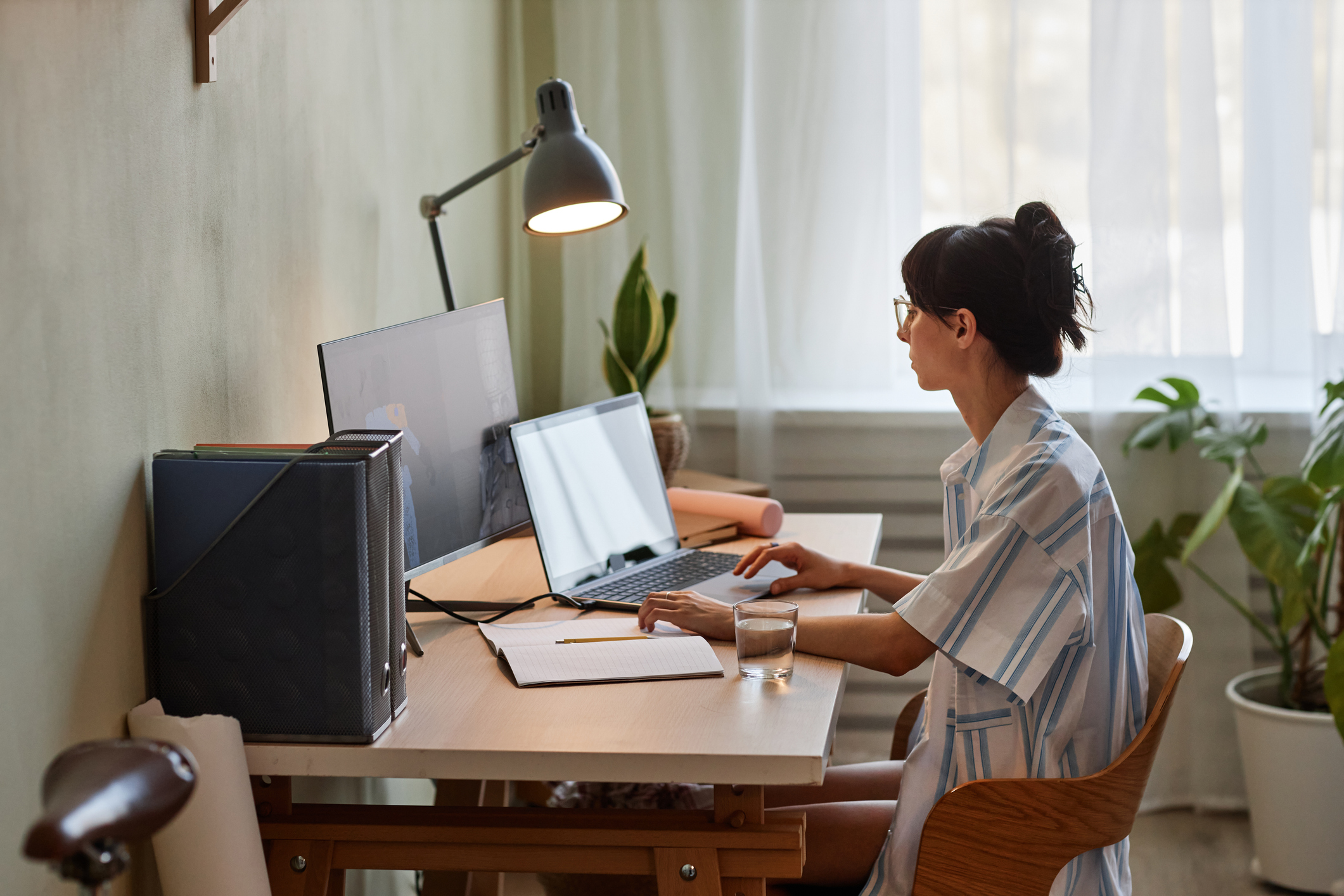 Female working at home using two screens