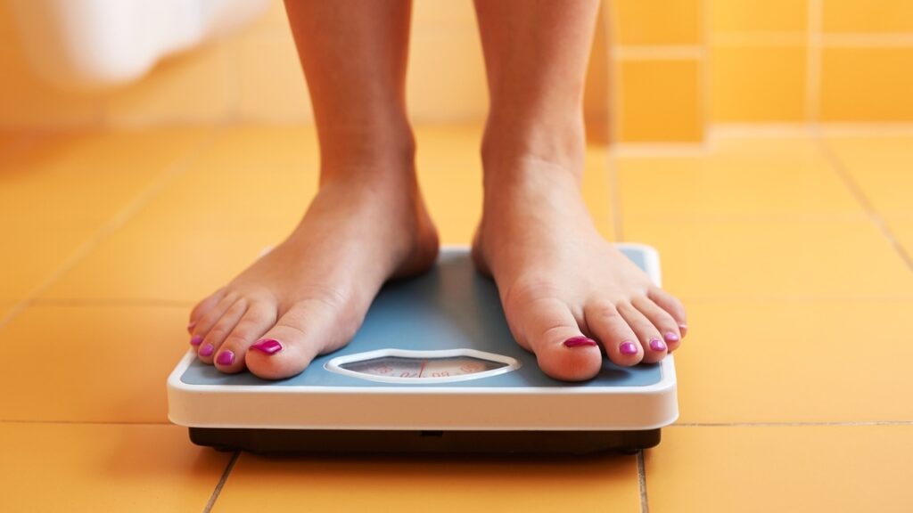 View of womans feet standing on weight scales