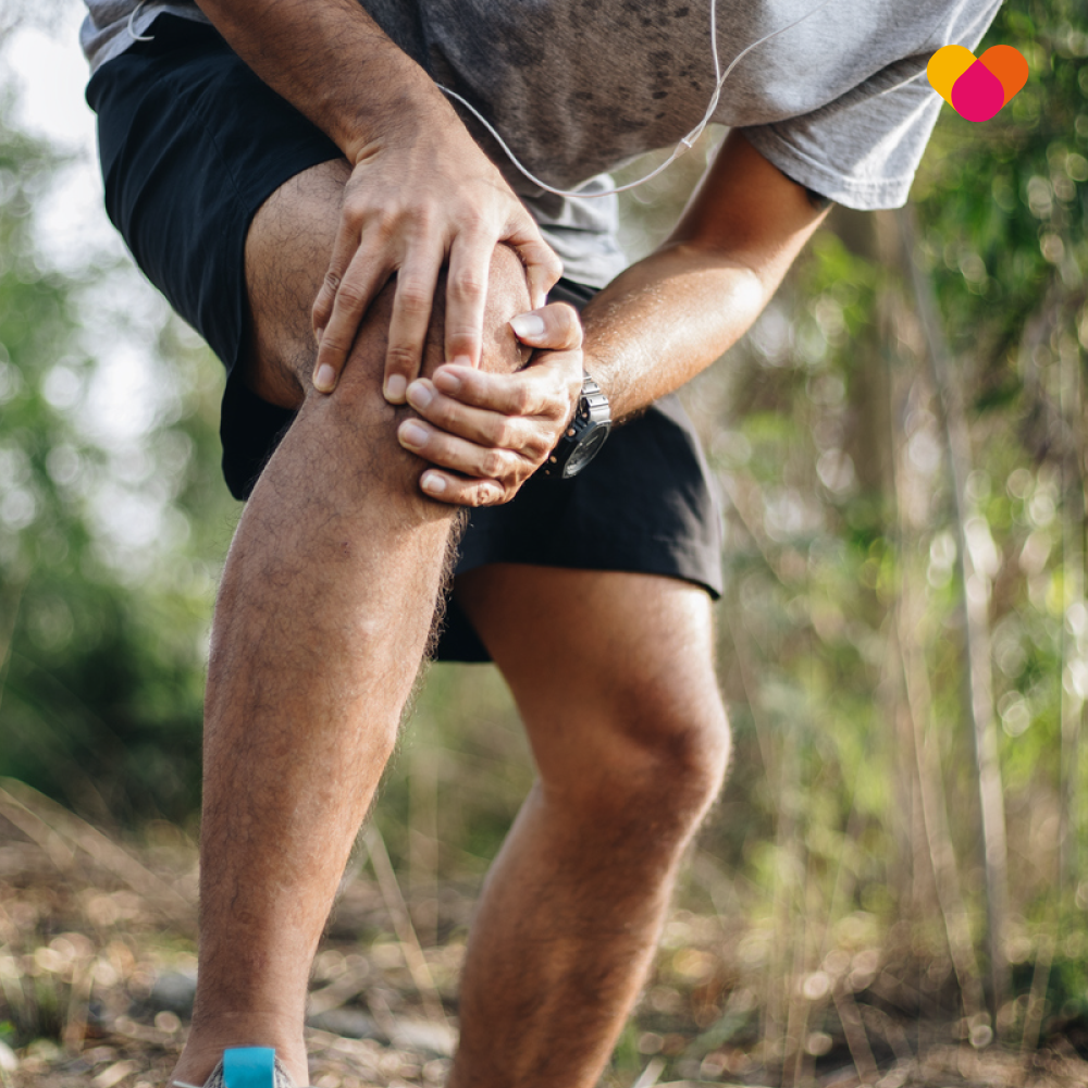 A man who is out jogging clutching his knee