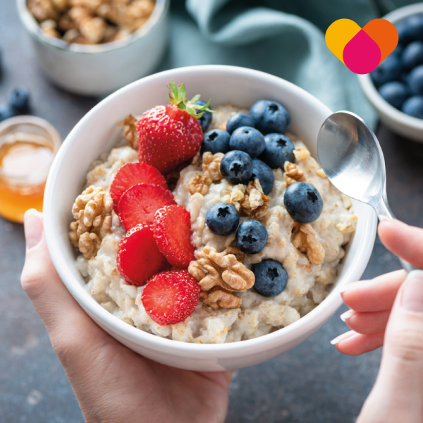 Woman eating a bowl of porridge with fruits and cereals